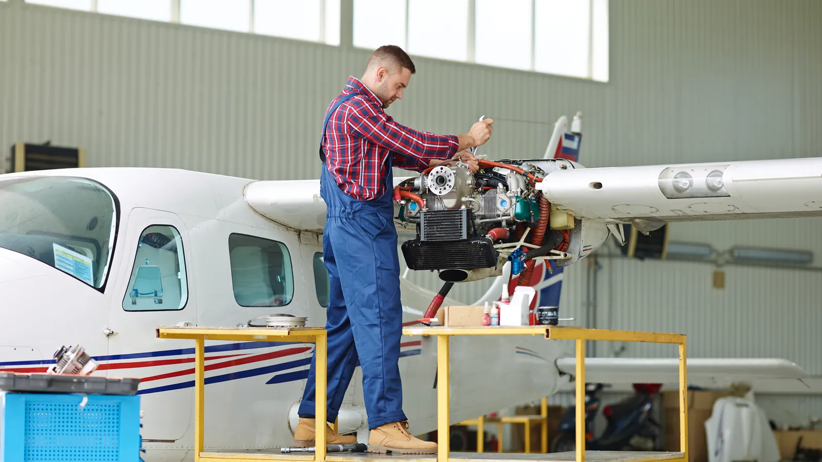 Perito aeronáutico revisando el motor de una avioneta en un hangar luminoso