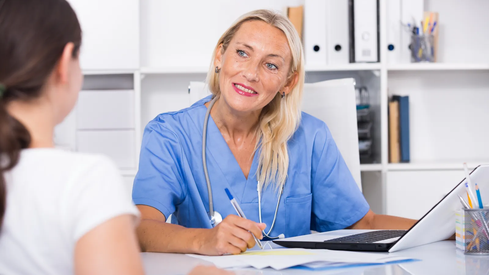 Médica sonriente atendiendo a una paciente en una consulta luminosa