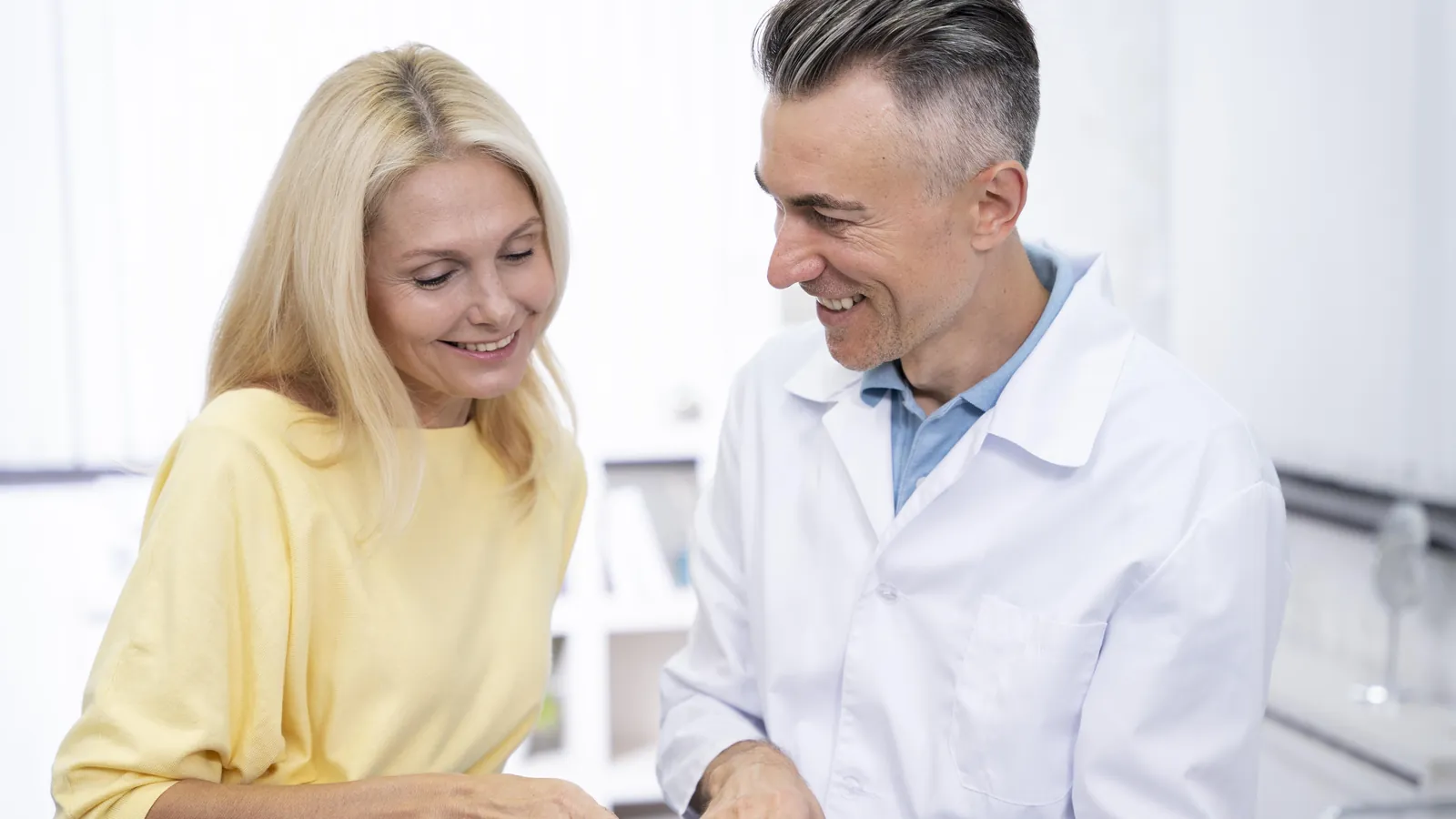 Médico sonriente explicando un informe en la tableta a una paciente