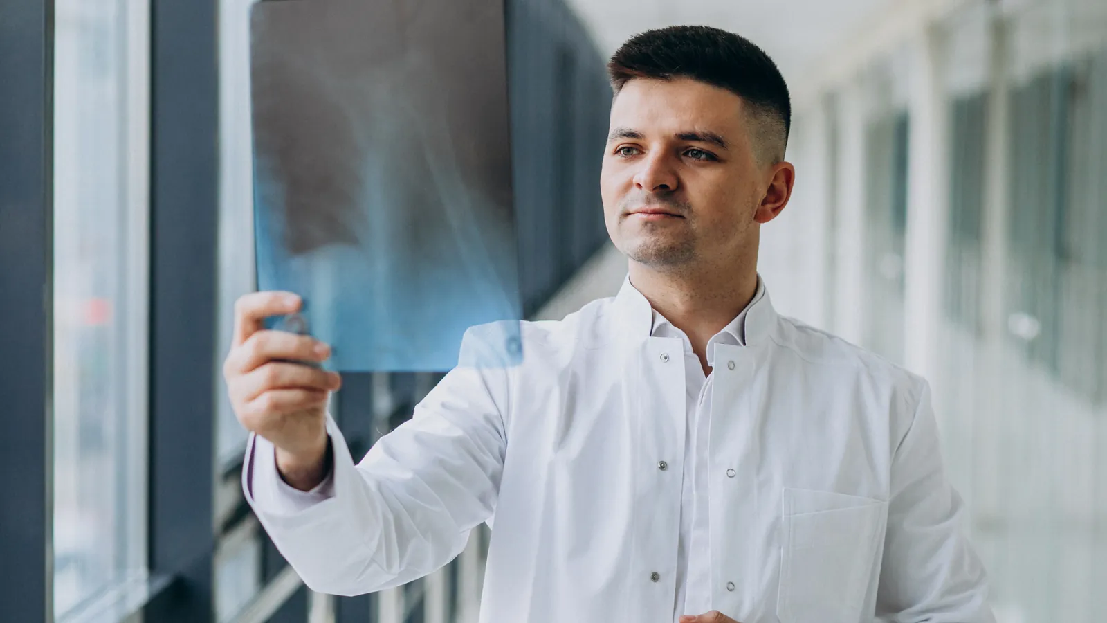 Perito médico revisando una radiografía junto a la ventana
