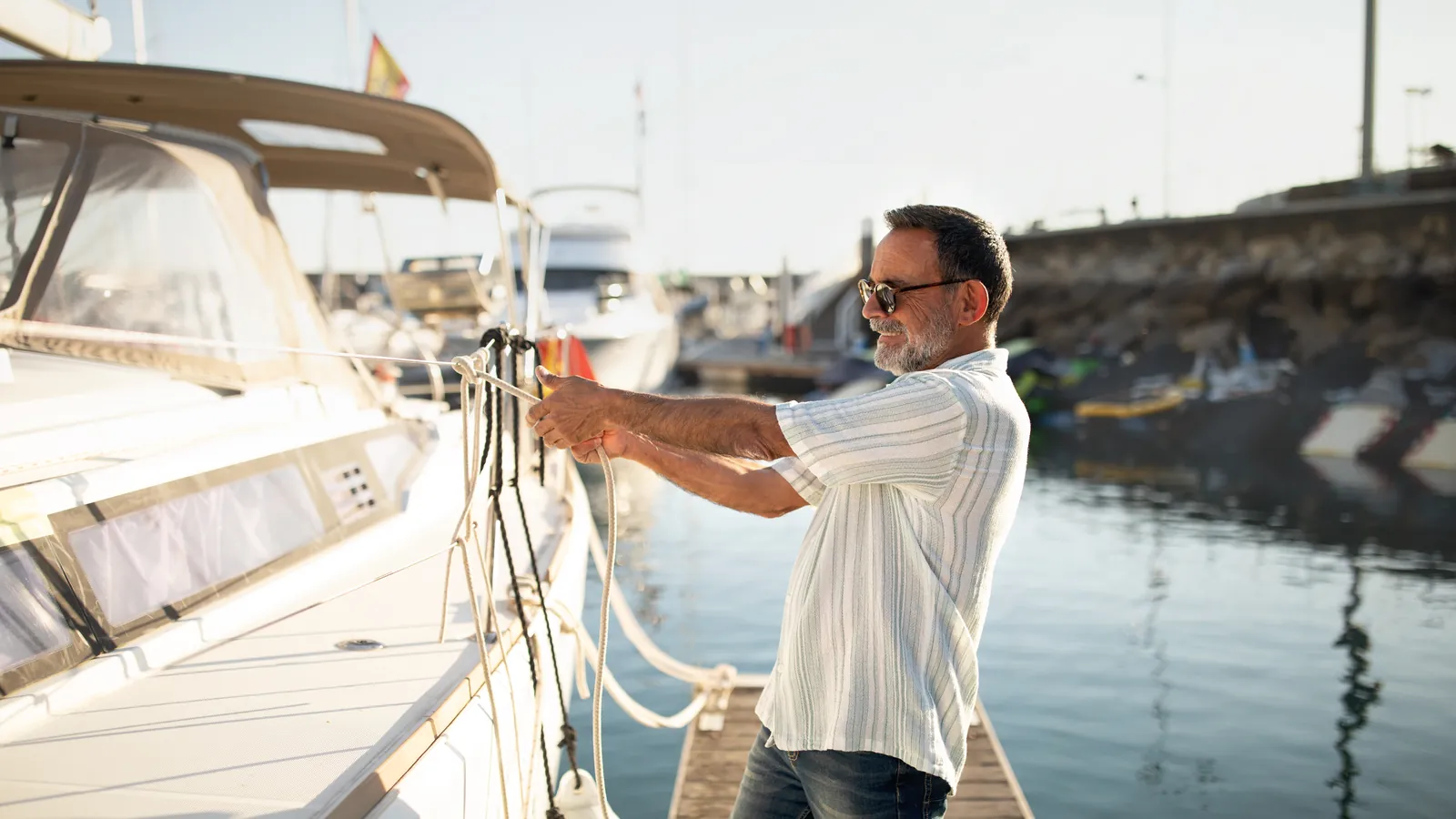 Propietario de un velero amarrando su embarcación en el pantalán de un puerto deportivo