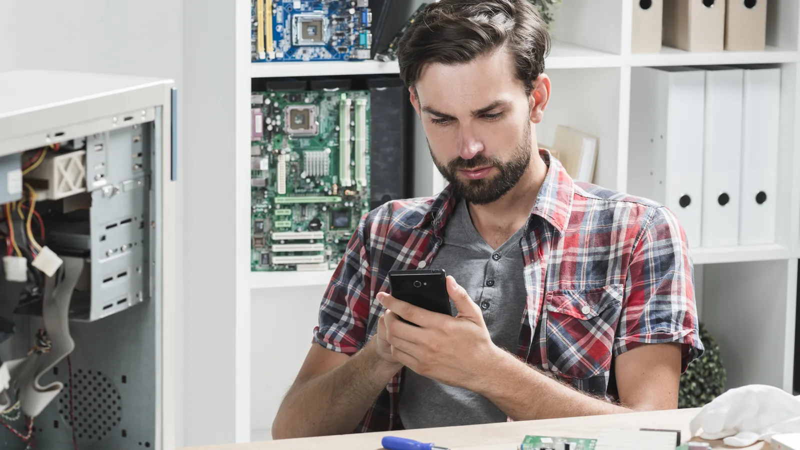 Perito informático revisando un teléfono móvil en su mesa de trabajo