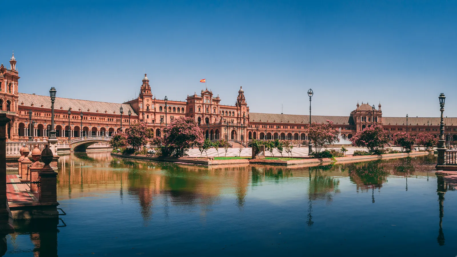 Plaza de España de Sevilla reflejada en el agua del canal en un día soleado