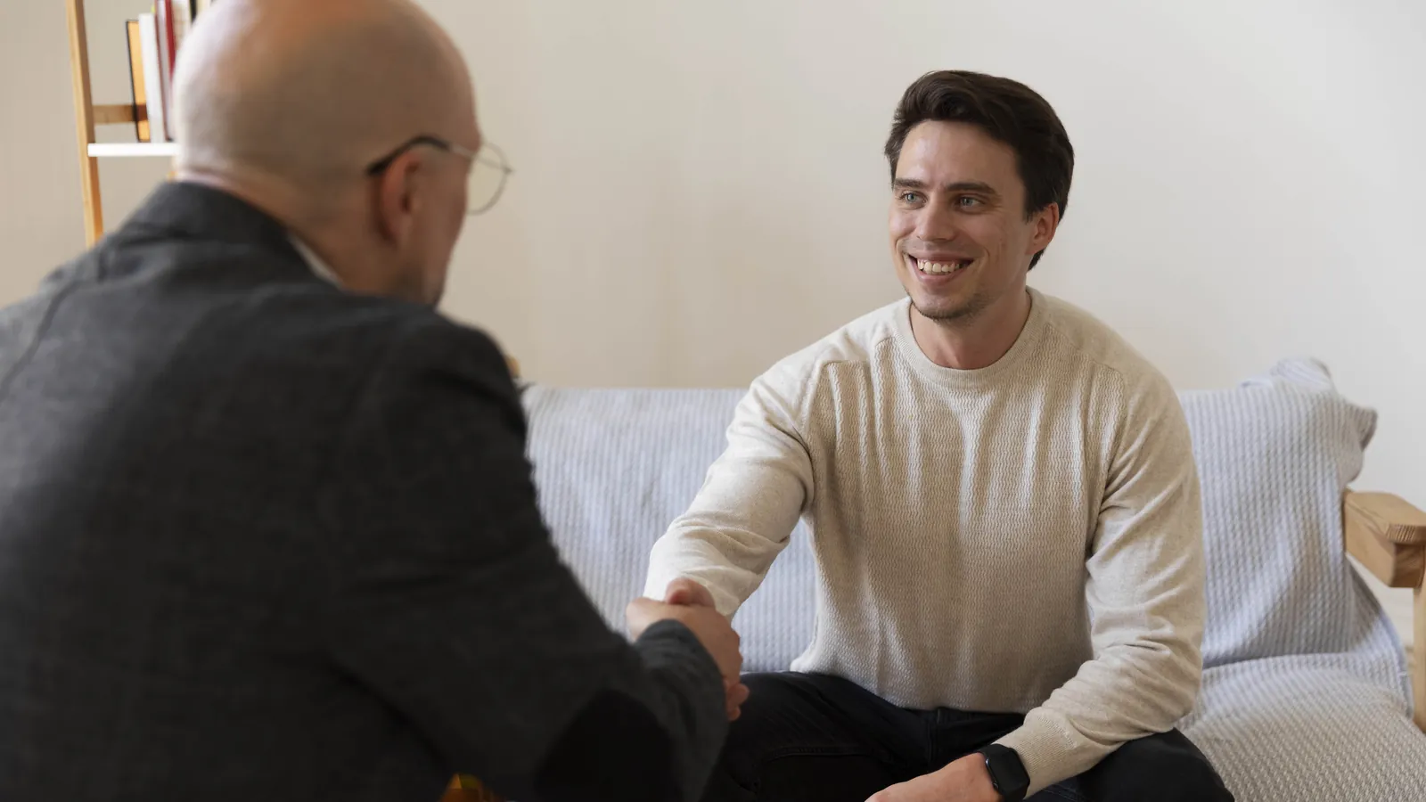 Psiquiatra estrechando la mano a un paciente sonriente al final de una conversación tranquila