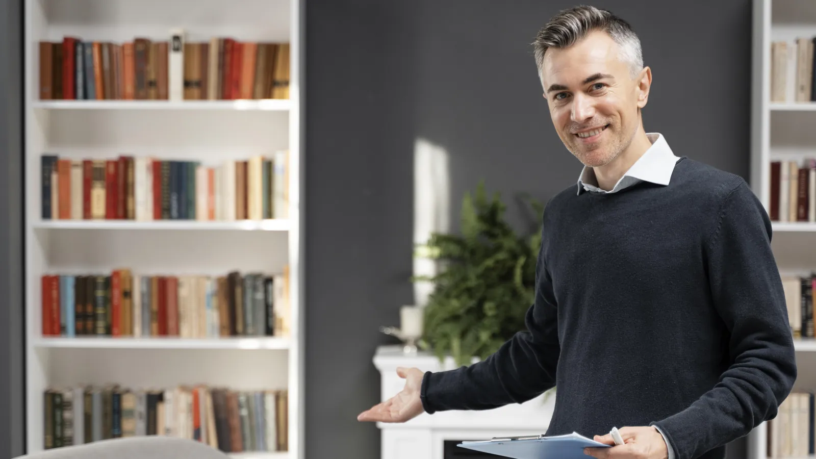 Perito psiquiatra sonriente invitando a pasar a su despacho, con estanterías de libros y una butaca
